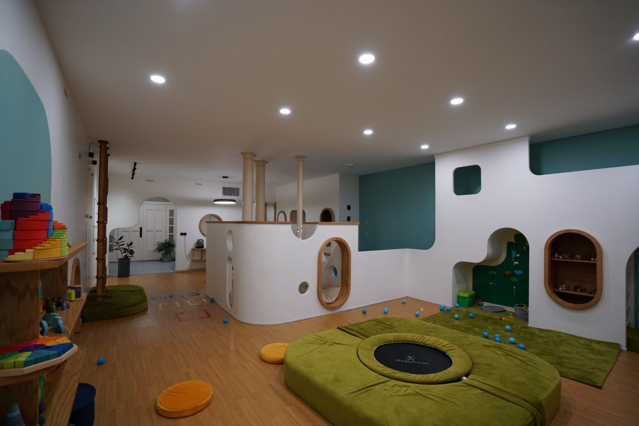 A built play space with a soft green mound and arches
