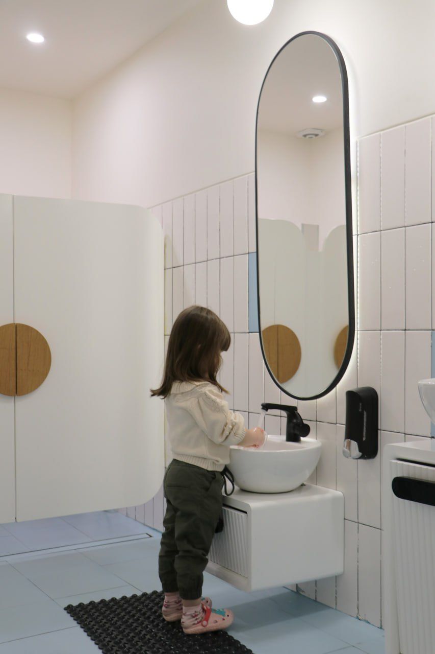 A child washing hands at a child-height basin